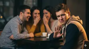 Home 19 Person looking uncomfortable, signaling refusal while friends laugh and gossip.