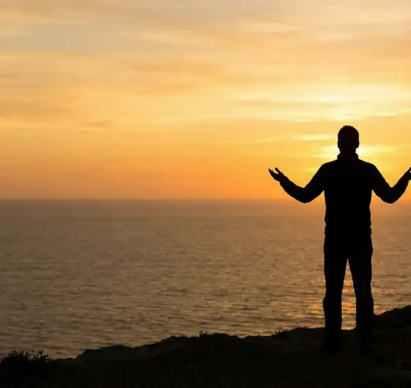 Ilustrasi Muslim berdiri di tebing saat senja, mengangkat tangan tanda berserah diri total kepada Rahmat Allah, sesuai doa Abu Bakrah.