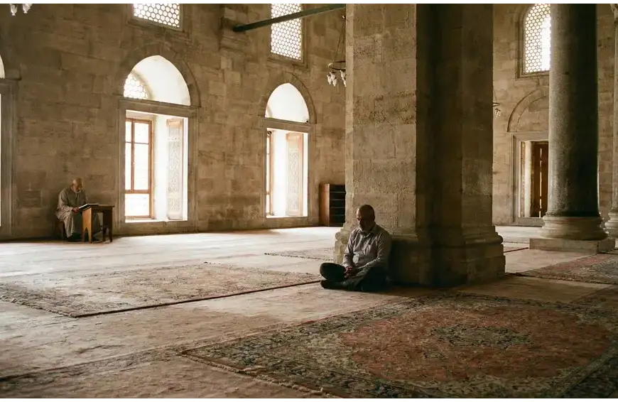 Home 27 A Muslim man sitting silently in a grand mosque, demonstrating the proper etiquette of I'tikaf through quiet contemplation and reverence.