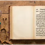 A flat lay photograph on a wooden table featuring an open antique Arabic Fiqh manuscript discussing the ruling of cupping (hijamah) while fasting, next to modern plastic cupping cups, a manual suction pump, and a wooden tasbih.