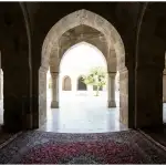 Pemandangan dari dalam masjid melihat ke arah luar gerbang, melambangkan batasan ketat hukum keluar masjid saat melaksanakan ibadah i'tikaf.