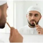 Seorang pria Muslim sedang membersihkan mulut dengan siwak sambil bercermin, ilustrasi menjaga kebersihan mulut saat puasa.Seorang pria Muslim sedang membersihkan mulut dengan siwak sambil bercermin, ilustrasi menjaga kebersihan mulut saat puasa.