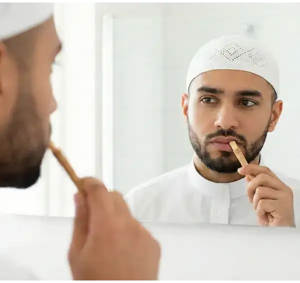 Seorang pria Muslim sedang membersihkan mulut dengan siwak sambil bercermin, ilustrasi menjaga kebersihan mulut saat puasa.Seorang pria Muslim sedang membersihkan mulut dengan siwak sambil bercermin, ilustrasi menjaga kebersihan mulut saat puasa.