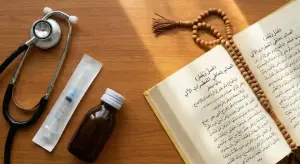 Home 13 A flat lay view on a wooden table, showing a stethoscope, a sterile syringe, a small brown medicine bottle, an open Arabic Fiqh book (Asna al-Matalib), and a string of prayer bead tasbih.