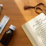 Apakah Suntik, Infus, dan Obat Tetes Membatalkan Puasa? Bedah Tuntas Kaidah Masuknya Benda ke Rongga Tubuh Peralatan medis seperti stetoskop, suntikan, dan obat botol di samping kitab kuning terbuka dengan tasbih di atas meja kayu.