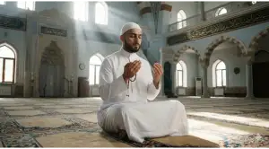 Seorang pria Muslim duduk khusyuk memegang tasbih di dalam masjid yang disinari cahaya matahari, melambangkan kesungguhan niat saat mengucapkan nadzar i'tikaf.