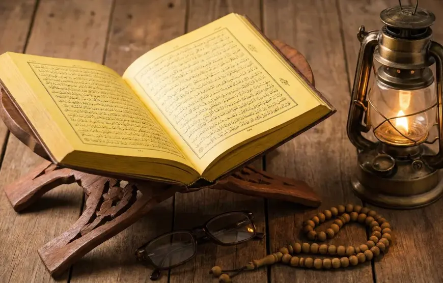 Home 9 "An open classical book on a traditional carved wooden stand, reading glasses, a string of tasbih beads, and a lit vintage brass lantern on a rustic wooden table surface."
