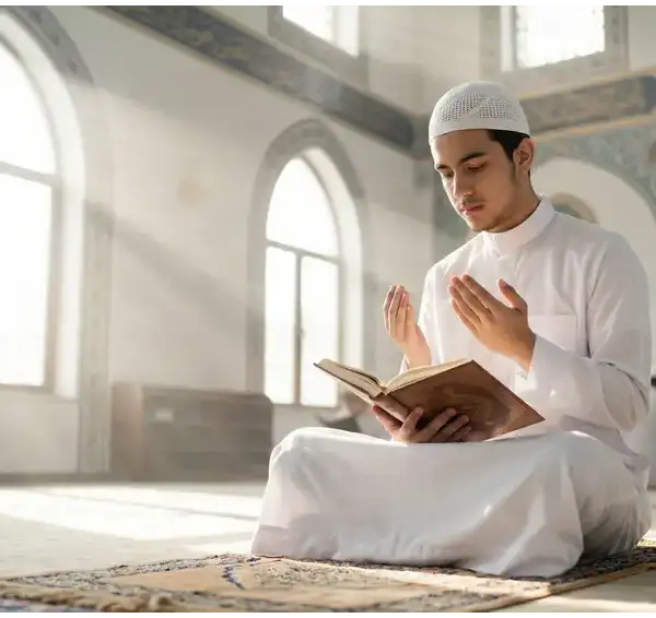 Home 3 A student of knowledge dressed in a clean white koko shirt sitting with proper etiquette in a brightly lit mosque prior to a majlis of knowledge.