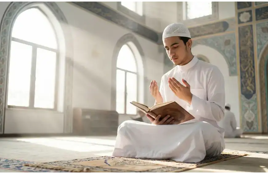 Home 39 A student of knowledge dressed in a clean white koko shirt sitting with proper etiquette in a brightly lit mosque prior to a majlis of knowledge.