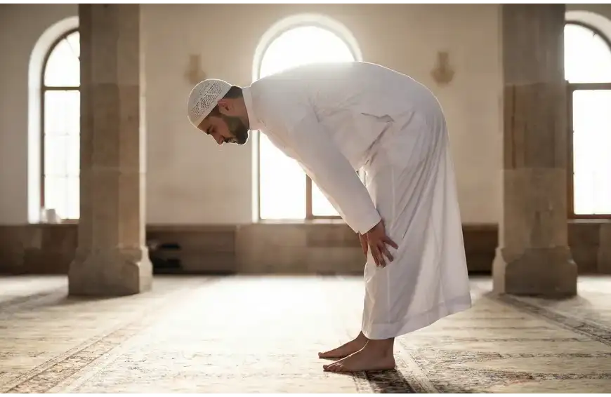 Home 9 A Muslim man demonstrating the perfect Ruku posture in prayer, featuring a straight back level with the neck and hands grasping the knees.
