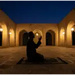 A lone Muslim kneeling in supplication on a prayer mat inside a mosque courtyard during the last third of the night, representing Salatul Hajah.