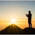 A silhouette of a Muslim praying with raised hands on a mountain at sunrise, symbolizing hope within the requirements of sincere repentance (taubatan nasuha).