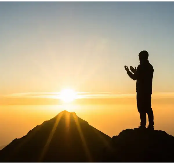 A silhouette of a Muslim praying with raised hands on a mountain at sunrise, symbolizing hope within the requirements of sincere repentance (taubatan nasuha).