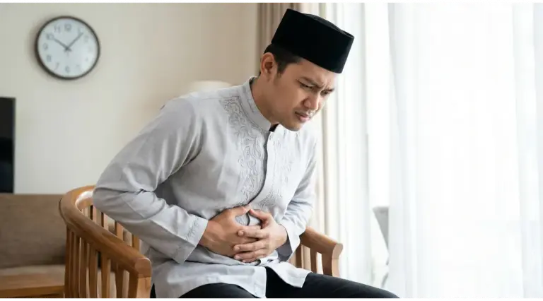 Home 1 vomit while fasting: Neatly dressed Muslim man holding his stomach, feeling nauseous while fasting during the day.