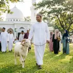 A neatly dressed Muslim man leading a Qurban ram in the morning after the congregation has finished the Eid al-Adha prayer.