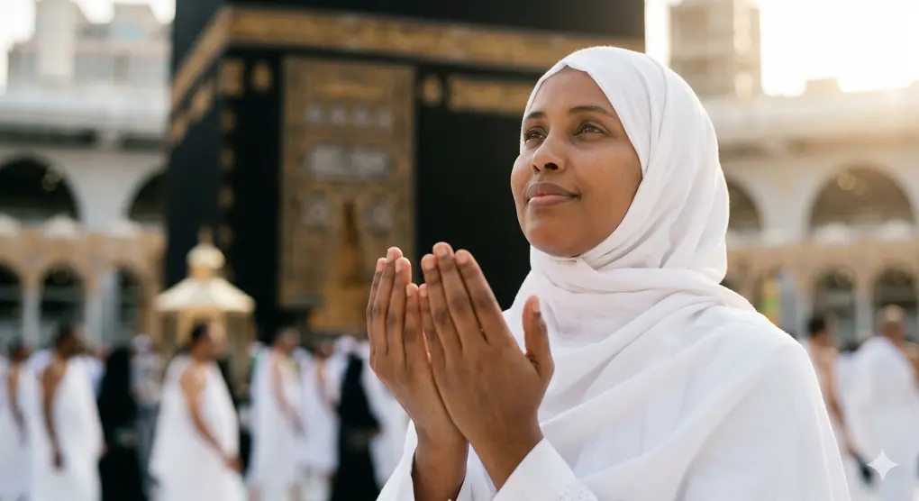 The Legal Basis of Hajj and Umrah in Islamic Jurisprudence 3 A Muslim woman in a white hijab raising her hands in sincere prayer in front of the Kaaba.