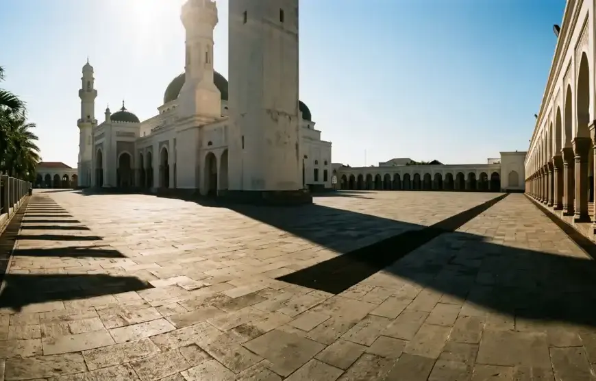 Kajian Fiqh Madzhab Syafi'i: Panduan Lengkap Hukum Islam, Doa, dan Tasawuf 25 Halaman masjid di siang hari yang terik dengan bayangan dinding yang memanjang — ilustrasi kondisi ibrad shalat Dzuhur