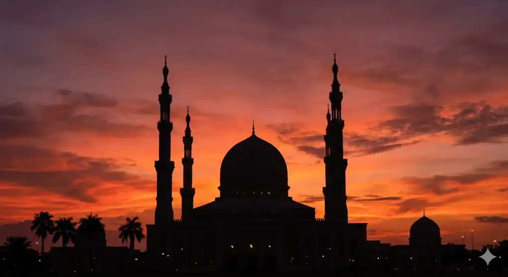 Siluet kubah dan menara masjid berlatar belakang langit senja oranye kemerahan tanda masuknya batas waktu shalat Maghrib