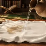 Meja kayu di ruang belajar pesantren dengan kitab fikih Arab klasik terbuka, kendi air, tasbih kayu, dan cahaya matahari pagi.